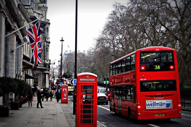 Red telephone boxes on a London pavement with a double-decker bus behind them